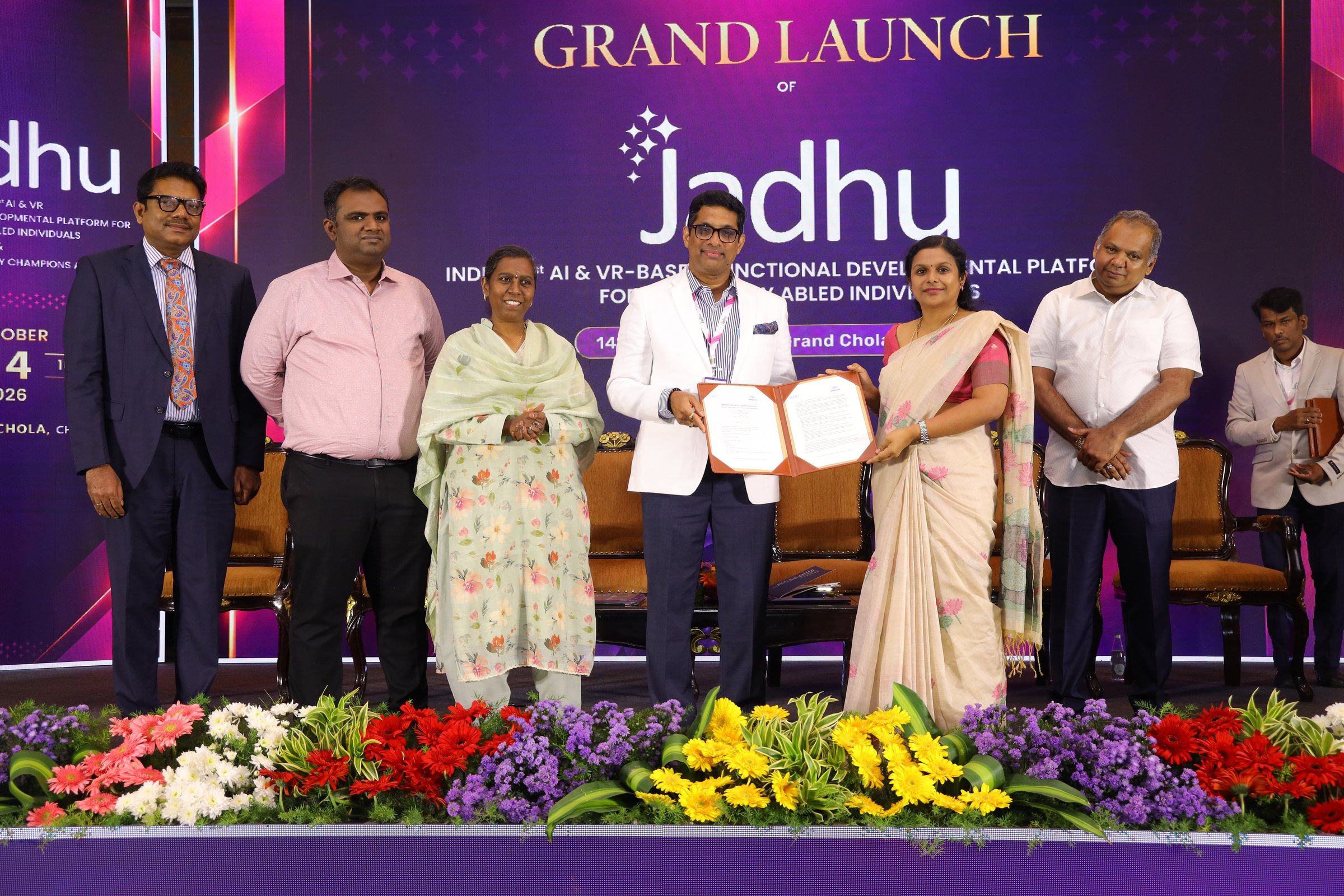 Signed Memorandum of Understanding between Jadhu and Aravind Eye Hospital, Madurai, held up on stage in front of the Jadhu event backdrop