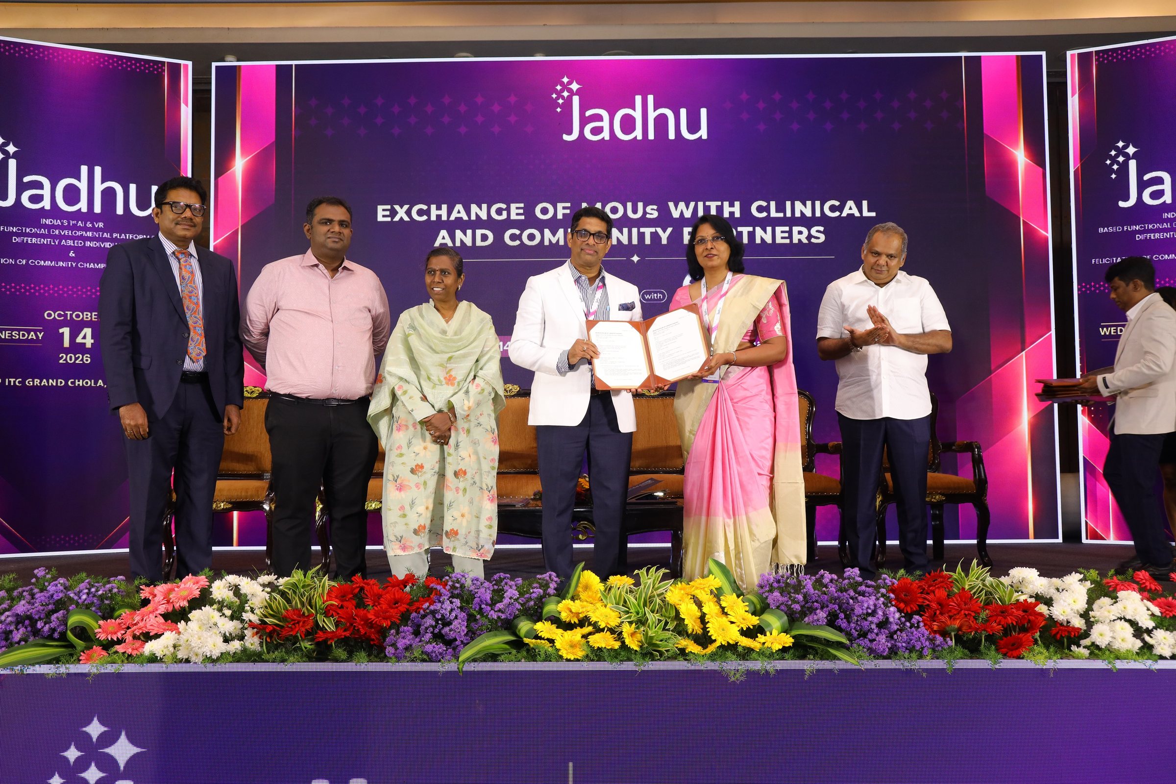 Signed Memorandum of Understanding between Jadhu and MERF Institute of Speech and Hearing, Chennai, held up on stage in front of the Exchange of MOUs backdrop